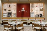 a dining room with tables and chairs and a large wall with art at NOUN Hotel, Norman, a Tribute Portfolio Hotel in Norman