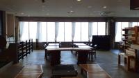 a large room with tables and chairs and windows at Marine Hotel Harimo in Hamada