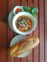 dois pratos de comida com uma tigela de sopa e um pão em Lucie Hotel em Vientiane