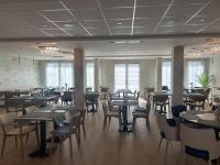 een restaurant met tafels en stoelen in een kamer bij DOMITYS - Margot in Ploufragan