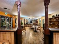 ein Restaurant mit Holzböden und Tischen und Stühlen in der Unterkunft Le Boréal in La Bastide-de-Sérou