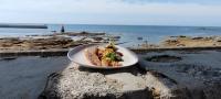 Un plato de comida sobre una roca cerca del océano. en Le Poisson d'Avril, en Le Guilvinec