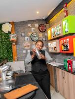 a woman standing in a kitchen drinking from a glass at Casa Mia Lodge & Restaurant in Blantyre