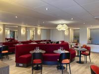 Un restaurante con un sofá rojo y mesas y sillas. en The Originals City, Hôtel Le Boeuf Rouge, Saint-Junien, en Saint-Junien