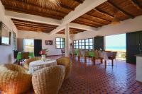 uma sala de jantar com cadeiras, mesas e janelas em Aura Tissa em Essaouira