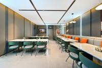 um restaurante com mesas longas e cadeiras verdes em Atour Hotel Beijing Liuli Bridge West Station em Pequim