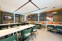 um restaurante com mesas longas e cadeiras verdes em Atour Hotel Beijing Liuli Bridge West Station em Pequim