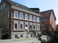 a large brick building with white windows on a street at Aalborg City Rooms ApS in Aalborg