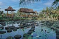 een vijver in een tuin met een tuinhuisje bij The Fire Flies Garden Villa in Penginyahan