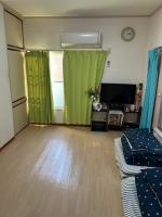 ein Wohnzimmer mit grünen Vorhängen und einem Flachbild-TV in der Unterkunft ハイツドリーム梦想小屋 in Tokio