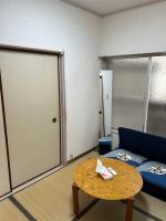 Zimmer mit Sofa, Tisch und Tür in der Unterkunft ハイツドリーム梦想小屋 in Tokio