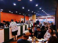 een groep mensen die aan een balie in een restaurant zitten bij The Brick-Road Penthouse in Kokomo