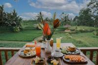 een houten tafel met borden eten en drinken bij The Fire Flies Garden Villa in Penginyahan