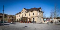 a large white building with a black roof on a street at Aare Lodge Attisholz Self Check-in in Luterbach