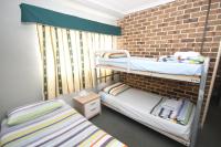 a room with two bunk beds and a brick wall at Acacia Snowy Motel in Jindabyne