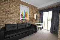 a living room with a black couch and a brick wall at Acacia Snowy Motel in Jindabyne