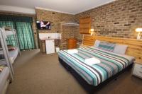 a bedroom with a bed and a brick wall at Acacia Snowy Motel in Jindabyne