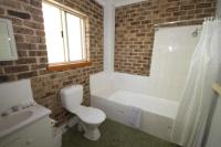 a bathroom with a white toilet and a bath tub at Acacia Snowy Motel in Jindabyne