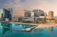 a city skyline with a boat in the water at Beach Rotana – All Suites in Abu Dhabi