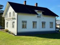 a white house with a black roof on a lawn at Sörnäsgården Bed & Breakfast in Lima