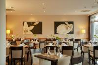 ein Esszimmer mit Tischen, Stühlen und Gemälden an den Wänden in der Unterkunft H+ Hotel Leipzig-Halle in Landsberg OT Peißen