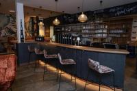 a bar with chairs and a counter with wine bottles at EGINO-Premium Hotel, Restaurant & Bar in Eggenburg