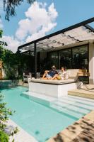 a man and woman sitting on a bench next to a swimming pool at Rosewood Phuket in Patong Beach