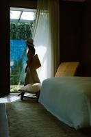 a woman walking out of a window in a bedroom at Rosewood Phuket in Patong Beach