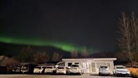 a group of cars parked in a parking lot under the aurora at Reykjadalur Guesthouse in Hveragerði
