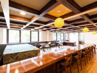 uma sala grande com um bar com cadeiras e mesas em ホテルオアシスガーデン em Obita