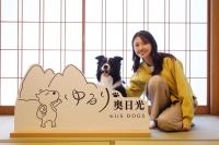 a woman sitting next to a sign with a dog at ゆるり奥日光withDOGS in Nikko