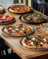 a table with several pizzas on plates on it at Albatross RELAX seaside design apartment with terrace in Ķesterciems