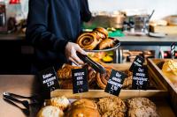 a person reaching for a tray of pastries in a bakery at The Social Hub Rotterdam Extended Stay in Rotterdam
