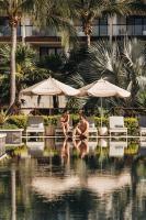 two people sitting next to a swimming pool with umbrellas at Unico Hotel Riviera Maya Adults Only in Akumal