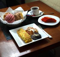 een tafel met een bord ontbijtproducten en een kopje koffie bij Hotel Boutique AB in Momoxpan