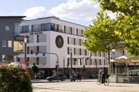 Gente montando bicicletas por una calle frente a un edificio en IBB Hotel Ingelheim, en Ingelheim am Rhein