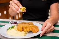 a person is holding a piece of food on a plate at Hotel Alpen Arnika in Tauplitzalm