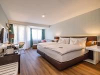 Una habitación de hotel con una cama grande y un escritorio. en Hotel Spalentor - Ihr sympathisches Stadthotel, en Basilea