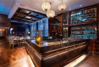 eine Bar in einem Restaurant mit Tischen und Stühlen in der Unterkunft Radisson Suites Bangkok Sukhumvit in Bangkok
