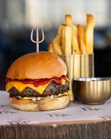 a cheeseburger on a table with a bucket of fries at The Unexpected Ibiza Hotel - Ushuaïa Club entrance included in Playa d'en Bossa