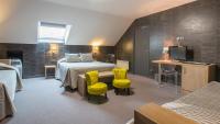 a hotel room with a bed and two yellow chairs at Hostellerie St Vincent in Nuits-Saint-Georges