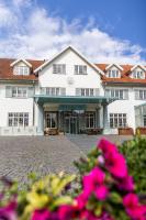 a large white building with pink flowers in the foreground at Hotel Fredensborg Store Kro in Fredensborg