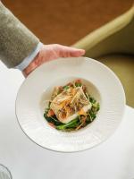 una persona que sostiene un plato blanco con un tazón de comida en The Fortingall, en Kenmore