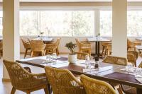 a dining room with tables and chairs and windows at Halotels Porto Myrina in Mirina