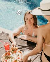 a woman sitting next to a pool with a plate of food at The Lume Boutique Hotel &amp; Restaurant &amp; Spa in Bodrum City