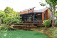 a house with a wrap around deck next to a pond at ธารคีรี รีสอร์ต สวนน้ำกำนัน in Ban Nai Sa