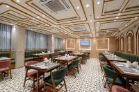 a restaurant with wooden tables and green chairs at Prarambh By Siara in Nadiad