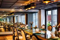 a restaurant with long tables and chairs and windows at Hotel de l'Opera Hanoi - MGallery in Hanoi