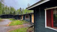 Un grupo de edificios negros con árboles al fondo. en Kyyronkaita, en Mikkeli
