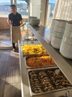 een man die naast een buffet met eten staat bij Yağcı Hotel Erdek in Erdek